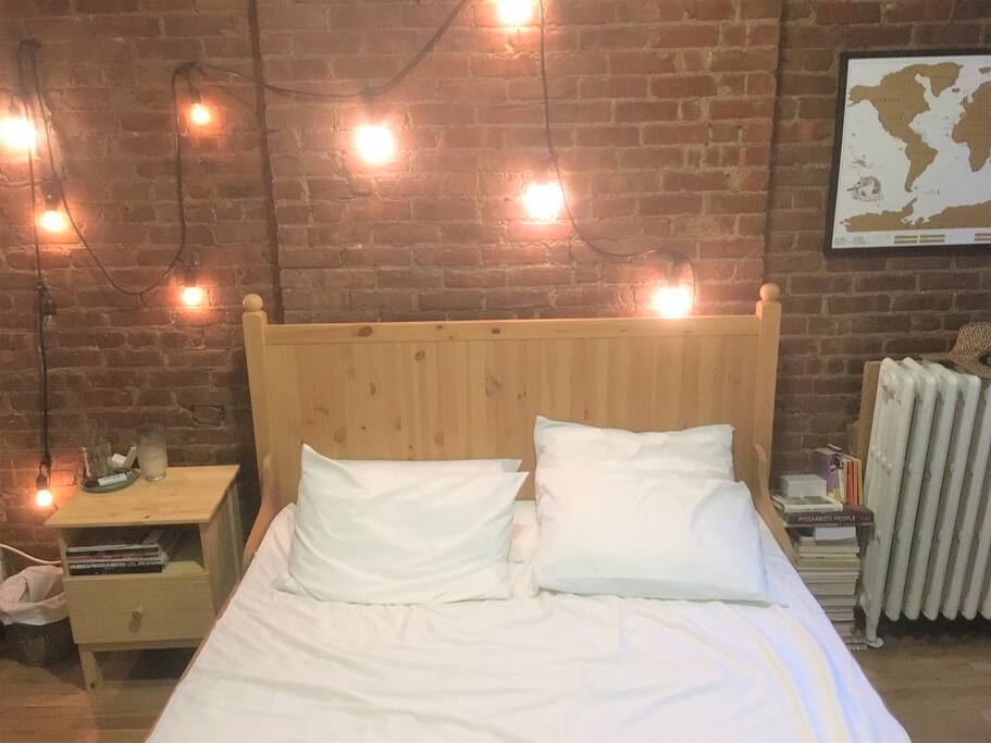 Private master bedroom with large queen bed and exposed brick.