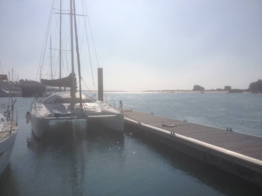 Le catamaran au ponton, avec, au fond, la Barre d'Etel, ouverte sur l'Océan Atlantique