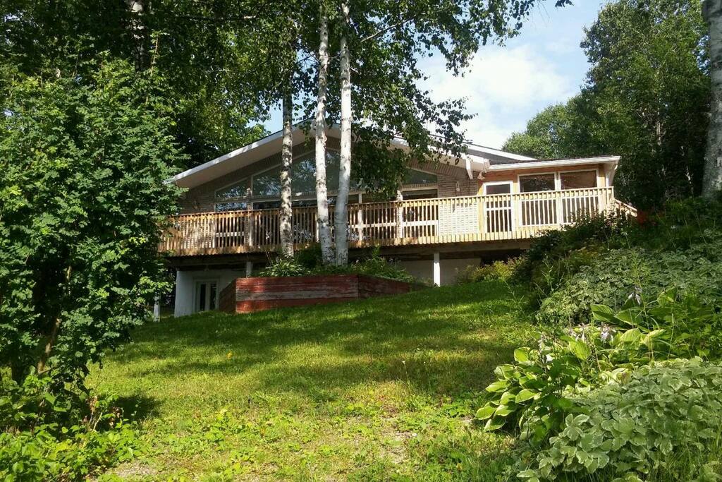 Front of house lakeside with a large deck and closed veranda 12' x 18' on the right hand side (no bugs) Walkout basement access door on left