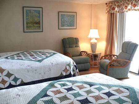 Large master bedroom with 2 queen beds, walk-in closet with washer and dryer, and sliding glass doors to patio and pool.