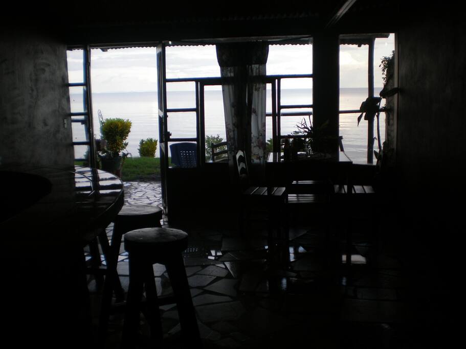 Large glass windows overlooking lake front with screens and screened door - wood tables, chairs, stools - clean and comfortable convenience