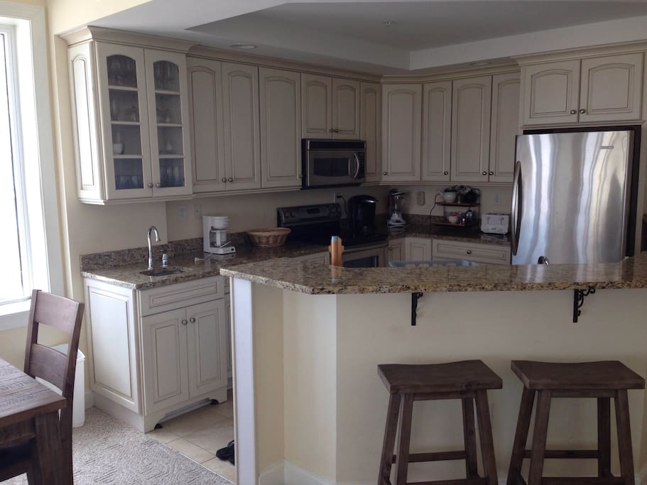 Open kitchen with all essentials, barstool seating, granite counter tops, stainless steel appliances, and a Keurig.