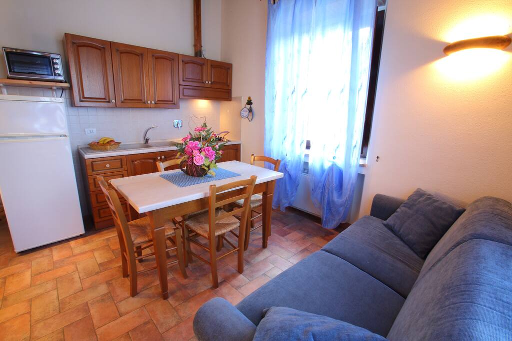 Soggiorno con cucina attrezzata e divano letto.