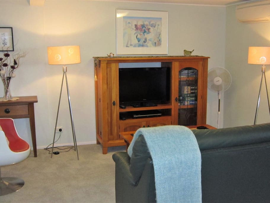 Living area. Ultra-fast wifi means your devices will stream movies easily. There are DVDs, books, puzzles and games in the TV cabinet and a wide range of tourist information in the hall table. There is a heat pump/AC unit and a movable pedestal fan.