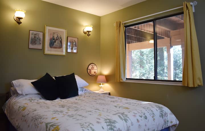 Მწვანე საძინებელში დგას საწოლი, პლეერი და უამრავი ბუნებრივი სინათლე.