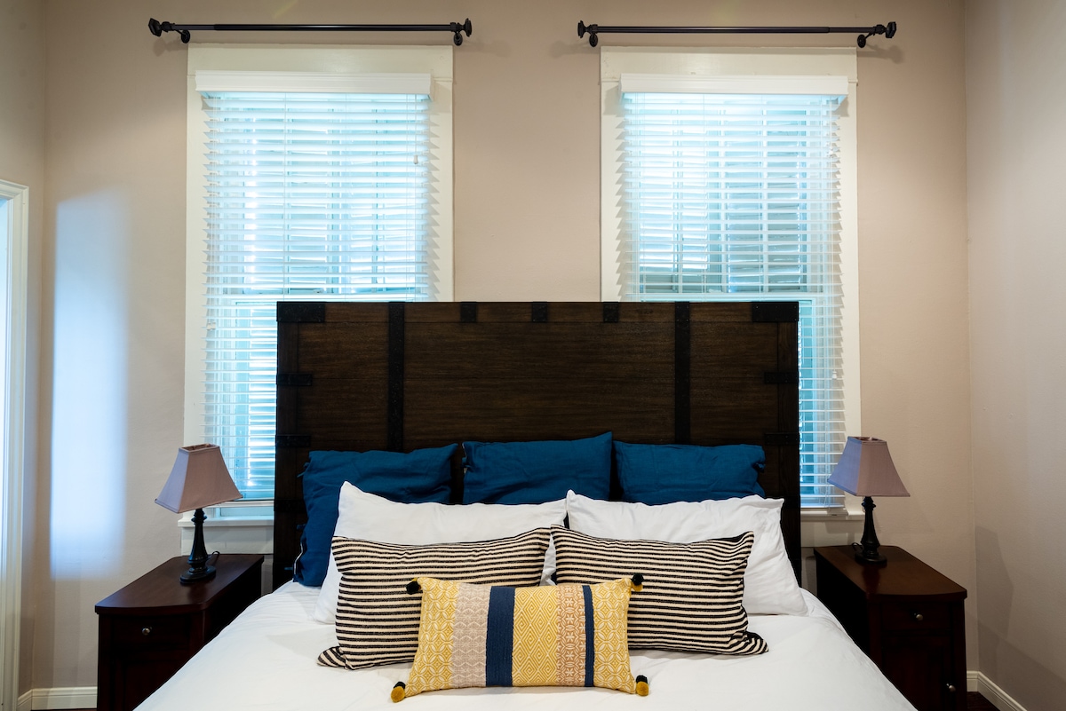 - นอนหลับสนิทในห้องพักที่มีสไตล์นี้ มีหัวเตียงที่โดดเด่นและหมอนหลายชั้นเพื่อความสะดวกสบายเป็นพิเศษ
- หน้าต่างคู่ให้แสงธรรมชาติและความสมมาตร
- โต๊ะข้างเตียงและโคมไฟที่เข้ากันช่วยให้ห้องดูสมดุลและใช้งานได้ดี