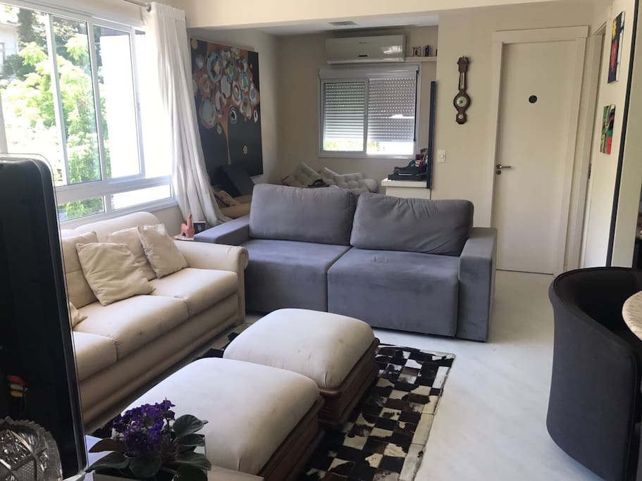 Sala com quarto integrado, sofás, televisão, TV a cabo, ar condicionado e mesa de mármore com 4 lugares