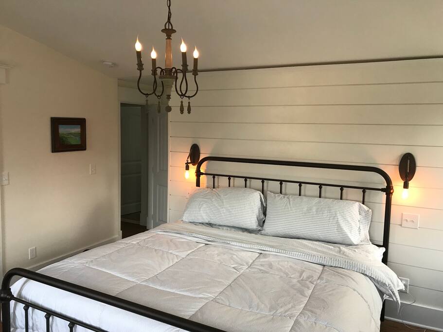 Master Suite King with shiplap accent wall, old filament sconces and chandelier