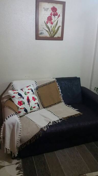 Sofá cama na sala, com ventilador de teto.