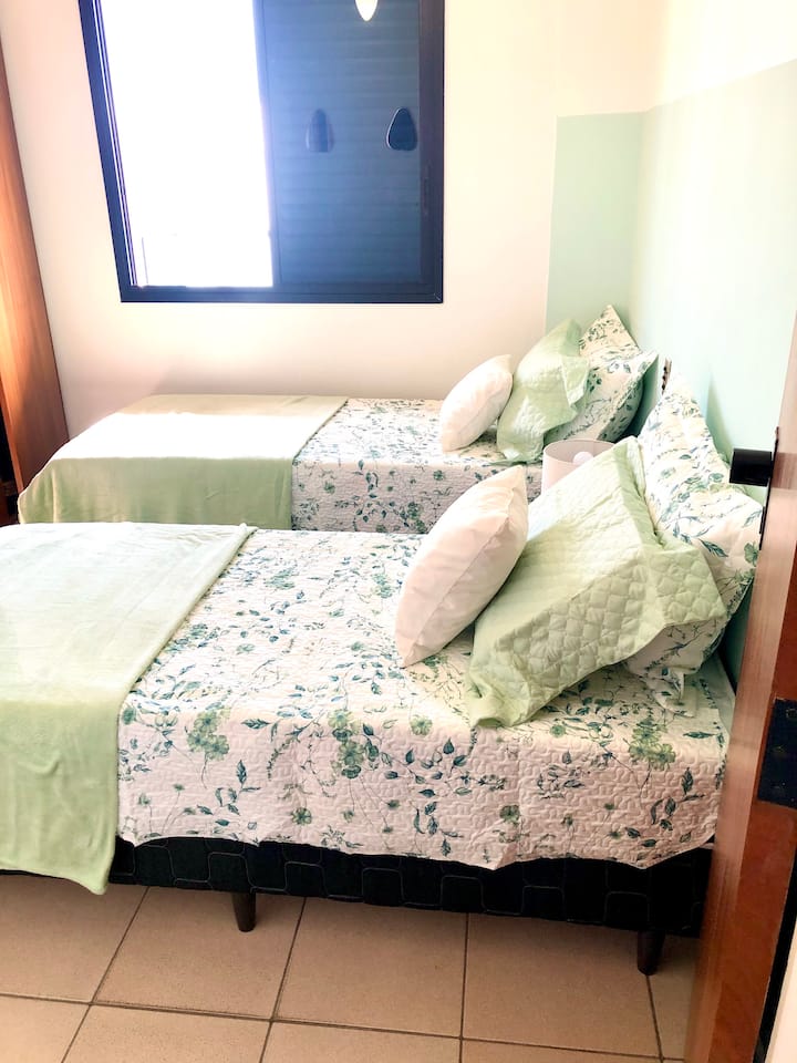 Chambre avec deux lits simples, armoires intégrées, ventilateur de plafond, climatisation. La fenêtre de cette pièce offre la vue de la balcon.