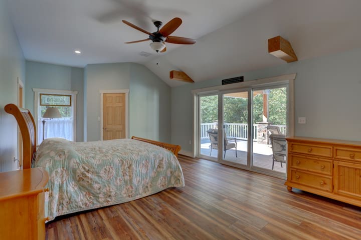 Chumba cha kulala cha ghorofa ya juu kina kitanda aina ya king kilicho na sehemu ya kutoka hadi juu ya sitaha na mwonekano wa bwawa.