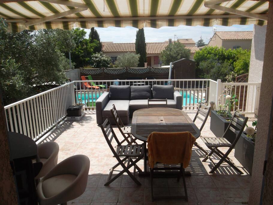 grande terrasse donnant sur la piscineavec son coin repas, son canapé pour se détendre et son bar