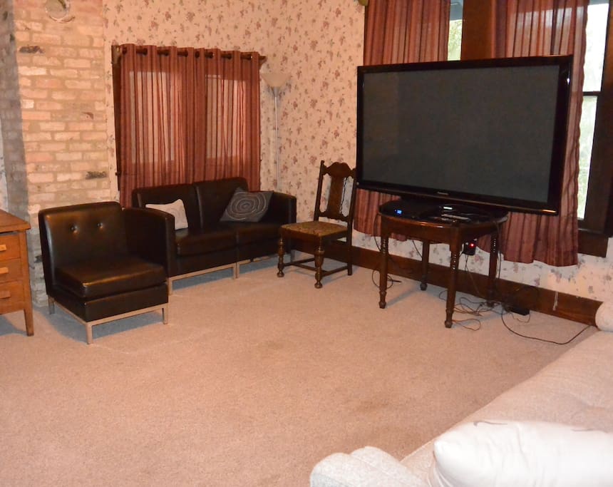 Living area with multiple couches, one of which is a futon. Large TV with cable.