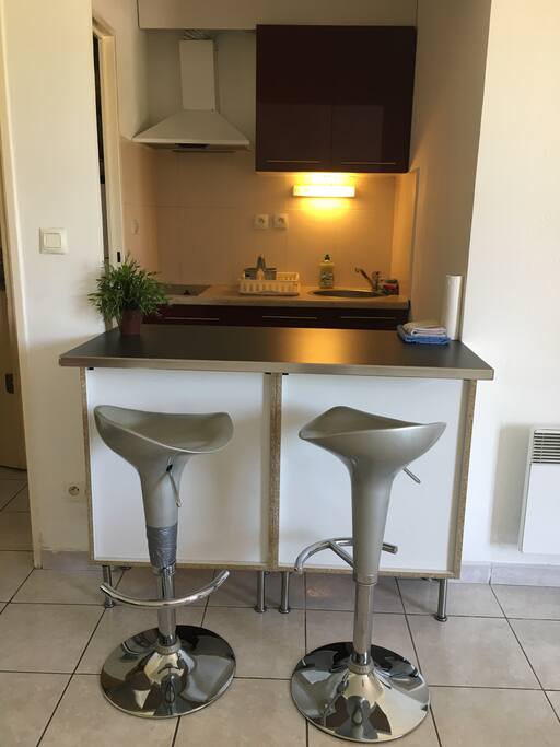 Cocina con pequeña barra y dos taburetes.
