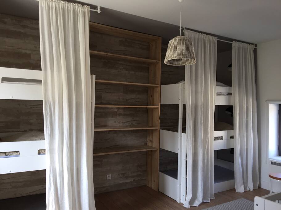 Un dortoir avec 6 lits confortables et petite lumière individuelle pour chaque lit.