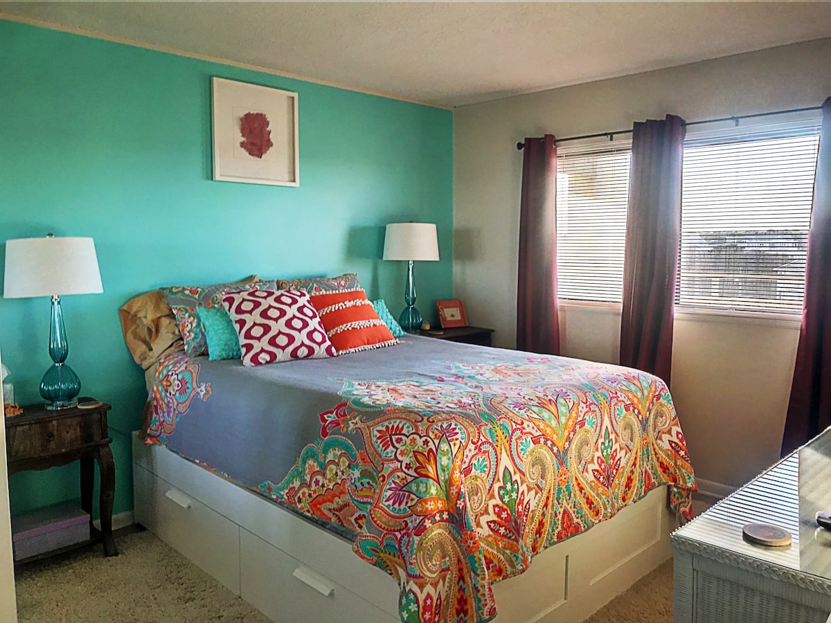 Dormitorio de invitados con cama tamaño queen y cortinas oscuras en la habitación.