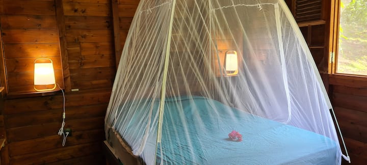La suite parentale: une chambre tout en bois avec un lit double sous moustiquaire