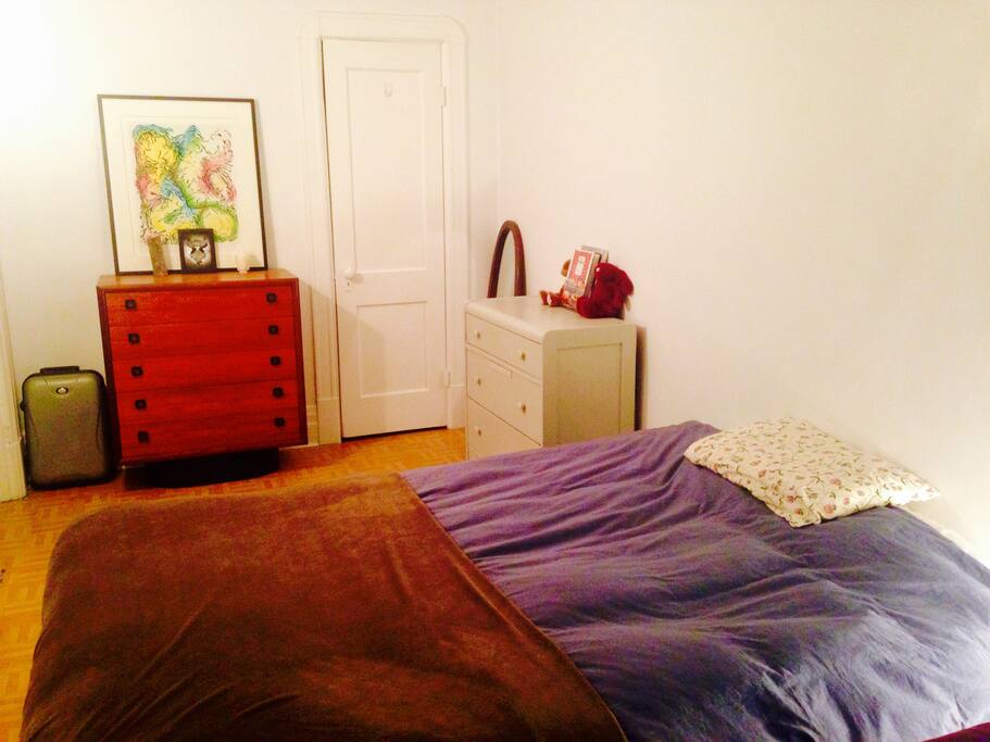 Chambre non-fermée avec lit Queen, commode à la disposition du voyageur.