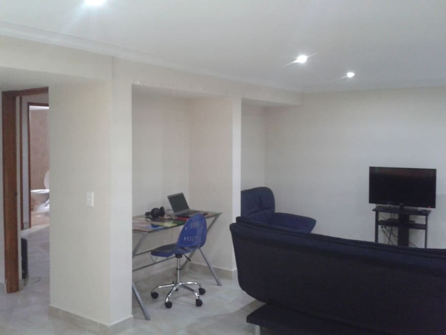 Living area with comfortable sofa, 32 Inch Cable TV, working desk and AC