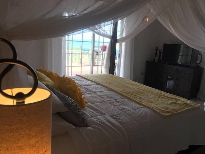 Master Bedroom en-suite. Check out the turquoise Caribbean Sea from the bedroom doors. Wake up this this every morning.
King size bed.
Individual AC's. Ceiling fan. Roku Smart TV w/Netflix & Youtube, music library. Private bathroom adjoins bedroom. 