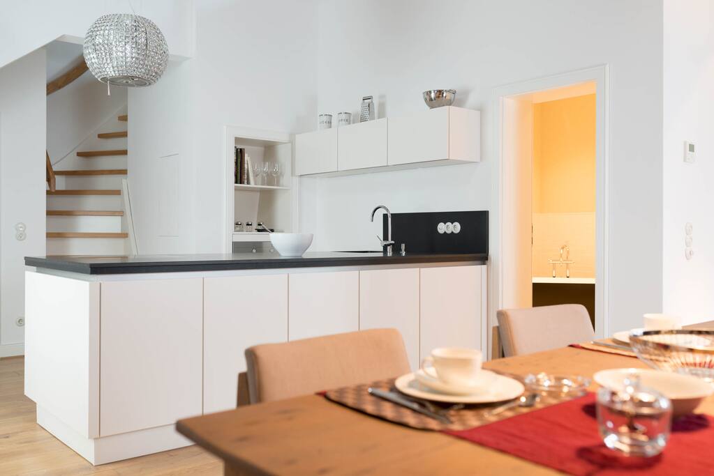 Blick vom Esstisch zur offenen Küche, Badezimmer und Aufgang zur Galerie.