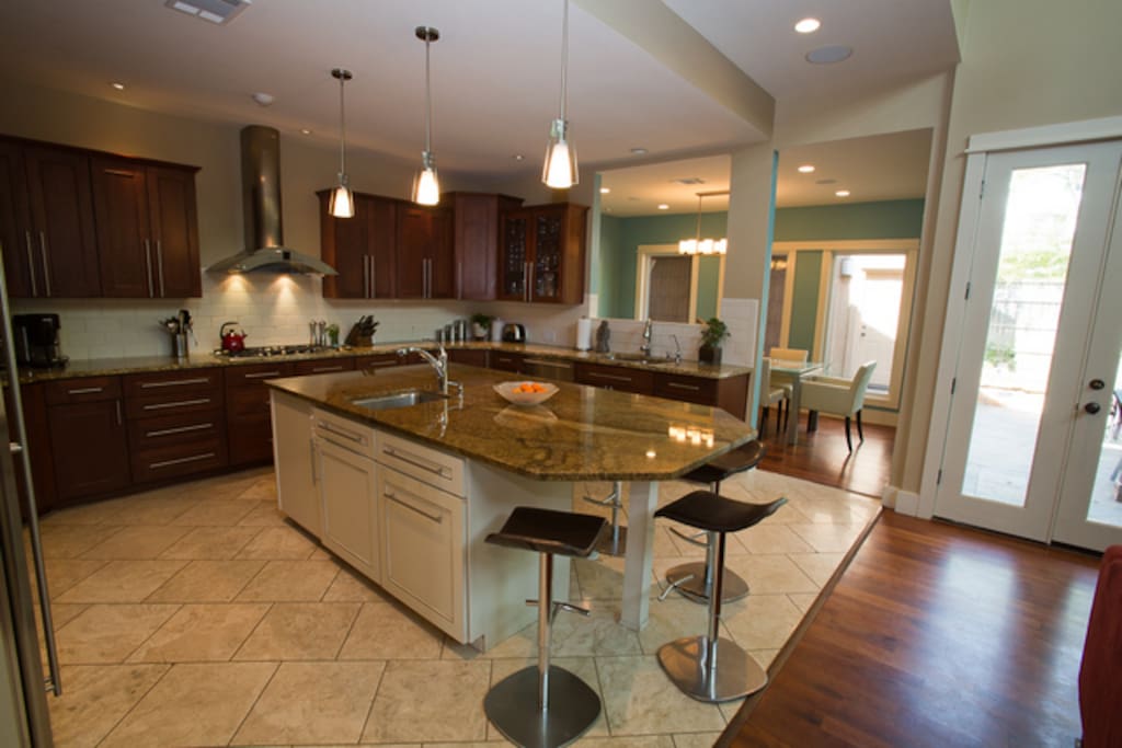 Large kitchen featuring island that seats 4, 2 sinks, stainless steel appliances, and granite