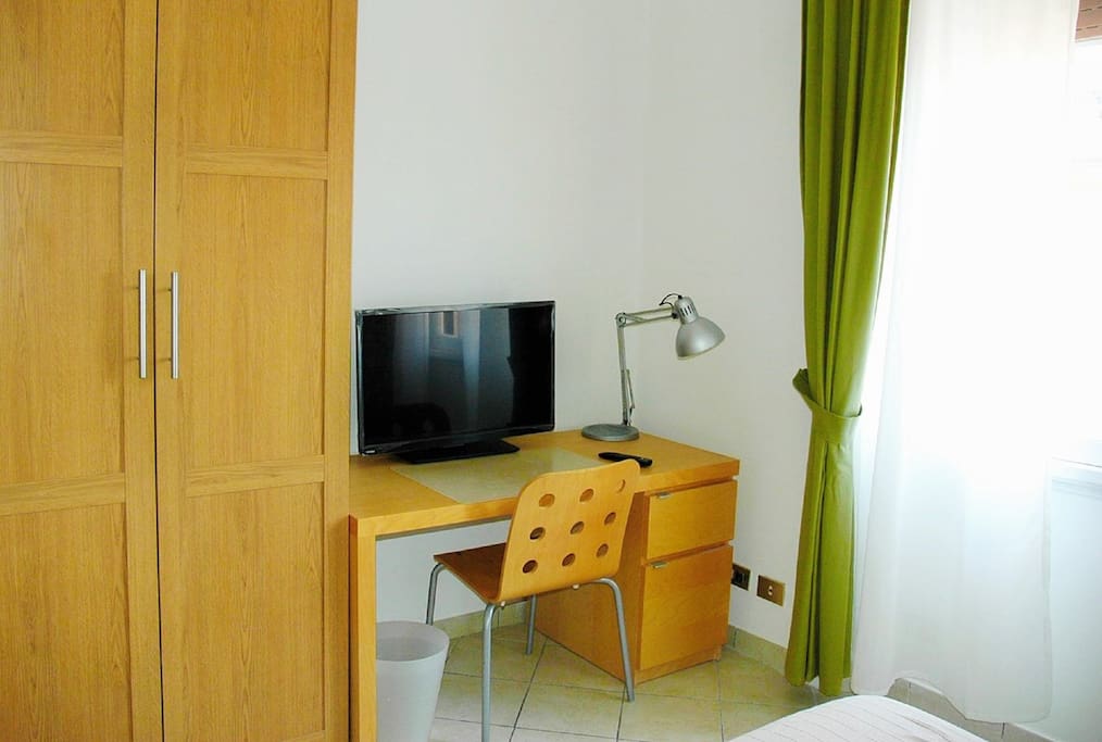 Camera oliva è dotata di ampia scrivania, armadio a due ante con cassetti e televisore LCD 30''
