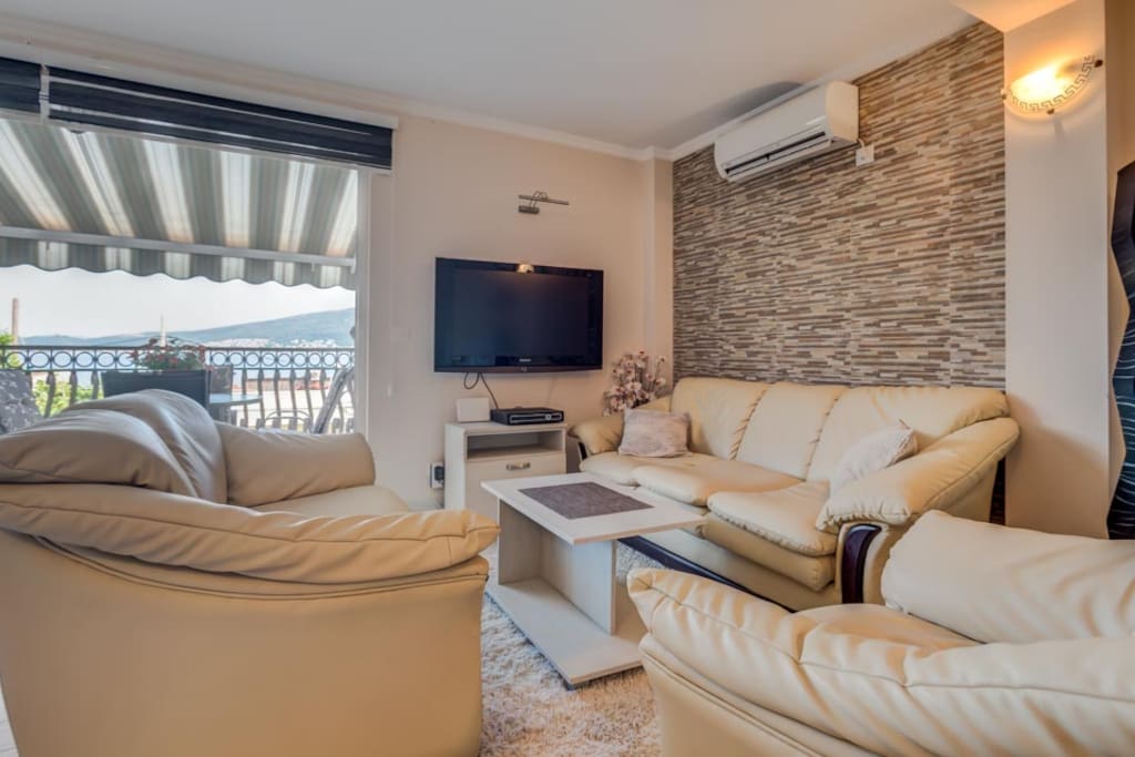 Living room area in earth tones, with comfort sofas and armchair, flat screen TV.
