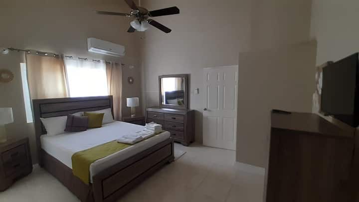 The master bedroom on upper floor with balcony, back yard/ mountain view, smart TV, a/c unit, fan and private bathroom