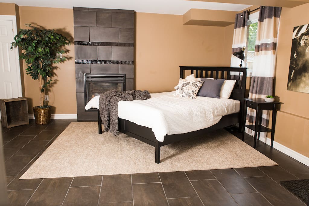 Cozy queen size bed with fireplace warmth.
