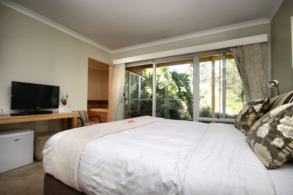 The luxurious bed looks out onto a private patio with gardens and outlook onto the forest guaranteeing a peaceful sleep