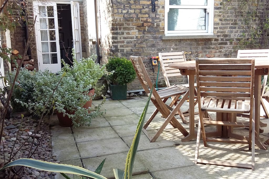 sunny garden with table and chairs looking back to French windows off dining room