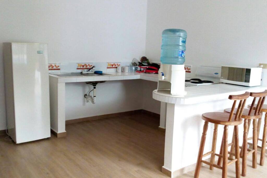 Area de Cocina con estufa, refrigeradora, microndas y utensilios de cocina