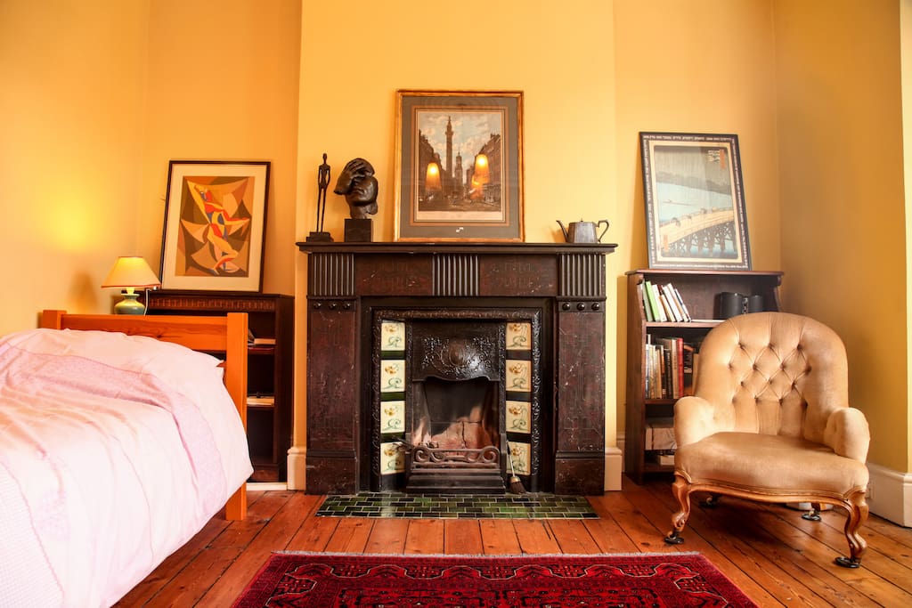 Lounge/living room with original Victorian fireplace. There is also a single bed which can be used as a sofa, as well as three armchairs and a desk.