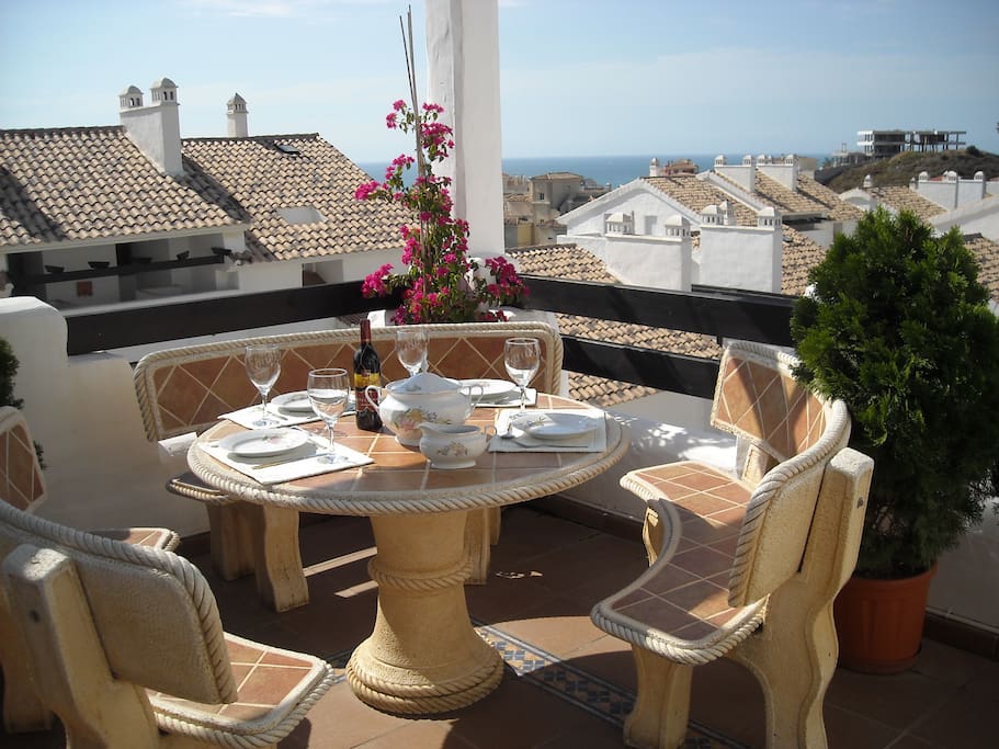 Spisebord på terrasse med utsikt til havet.