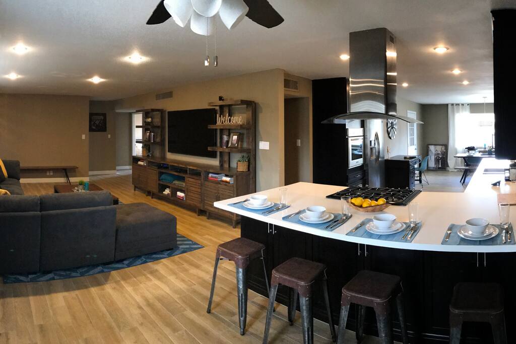Living room with dining table and open concept kitchen. Kitchen has all appliances and breakfast bar.