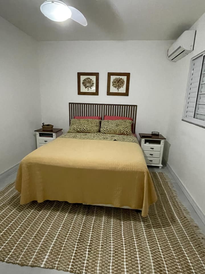 Schlafzimmer mit eigenem Bad, Boxspringbett, Nachttische, Sisalteppich und bei Klimaanlage.