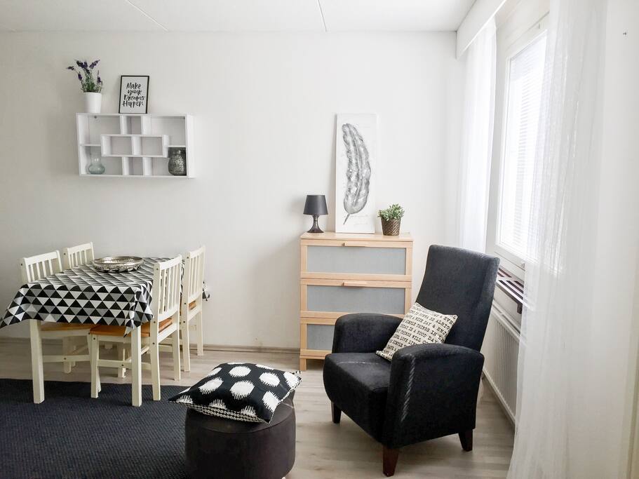 Oleskelutilassa neljän hengen ruokailuryhmä ja nojatuoli, lipastossa lisää säilytystilaa.