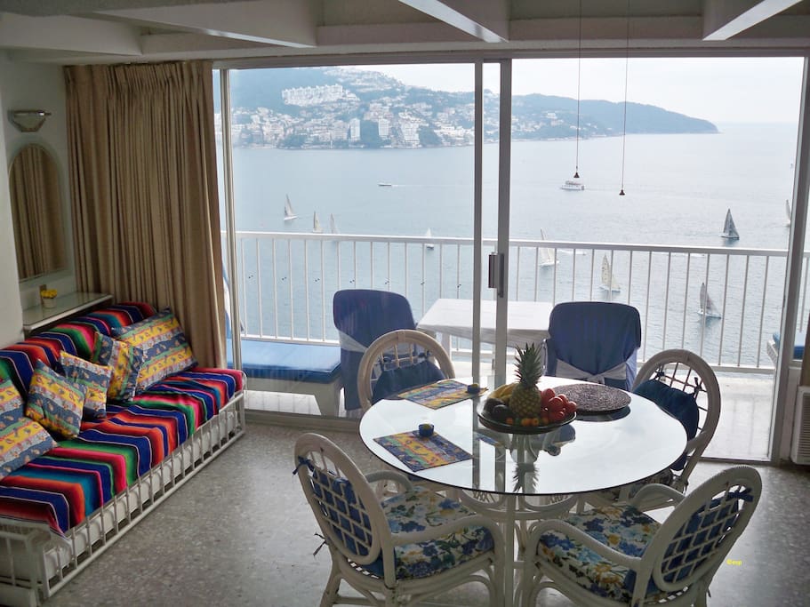Mexican wicker chairs, plate glass dining table, sailboats in Acapulco Bay