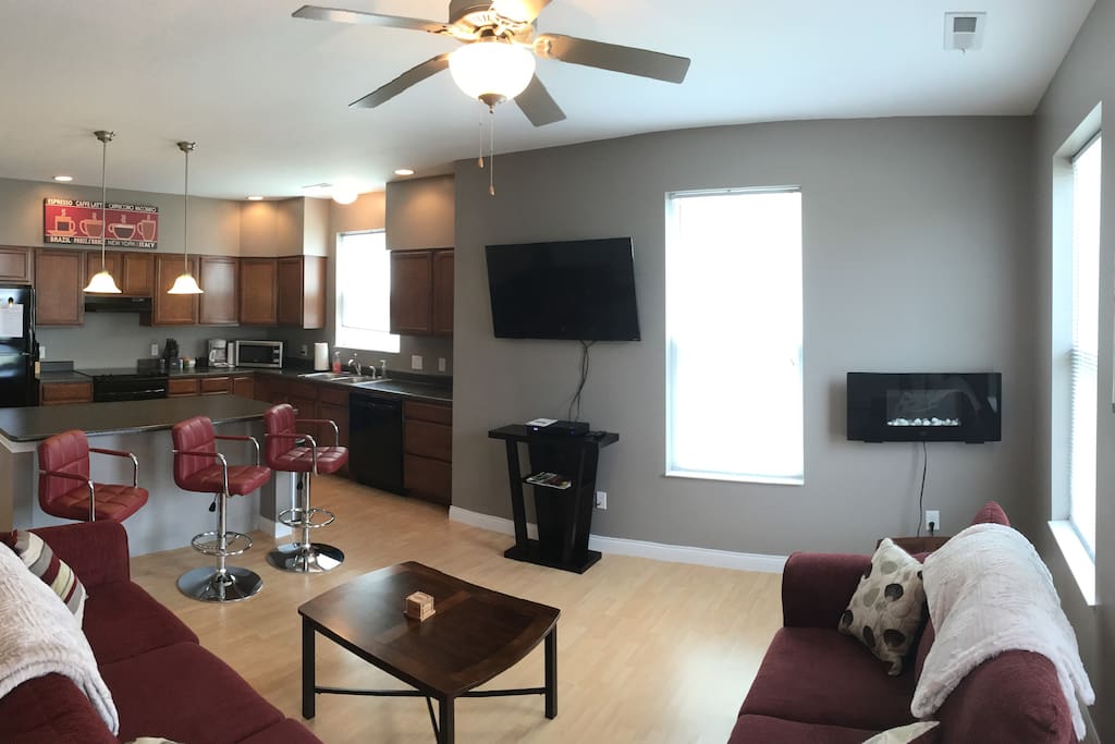 Panoramic photo of family room with 50" TV and kitchen...