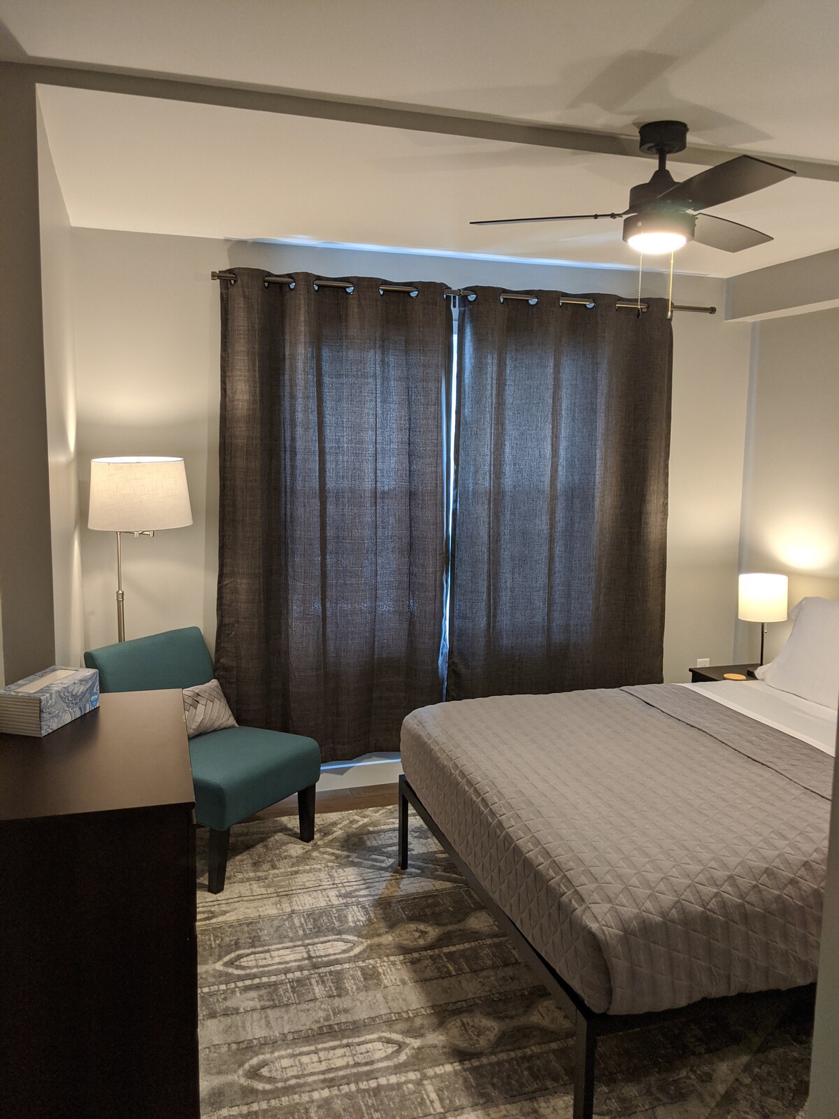 The second bedroom also has a comfortable chair and dresser.