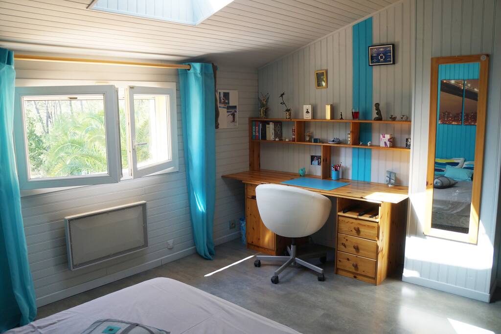 La chambre est très lumineuse avec bureau et étagères