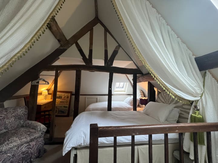 4. spavaća soba (bračni krevet) sa stepenicama koje se spuštaju s gornjeg kata (udesno). Dvokrevetna spavaća soba i privatna kupaonica nalaze se iza fotografa i kroz vrata.