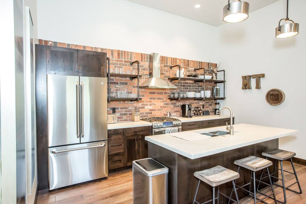 Kitchen features stainless steel appliances with brick backsplash.