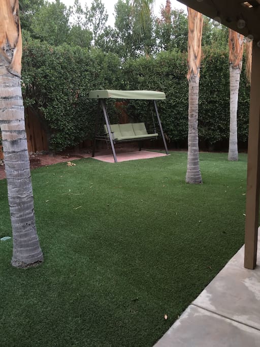 Private backyard w artificial turf, swing, covered patio w lights, table and chair
