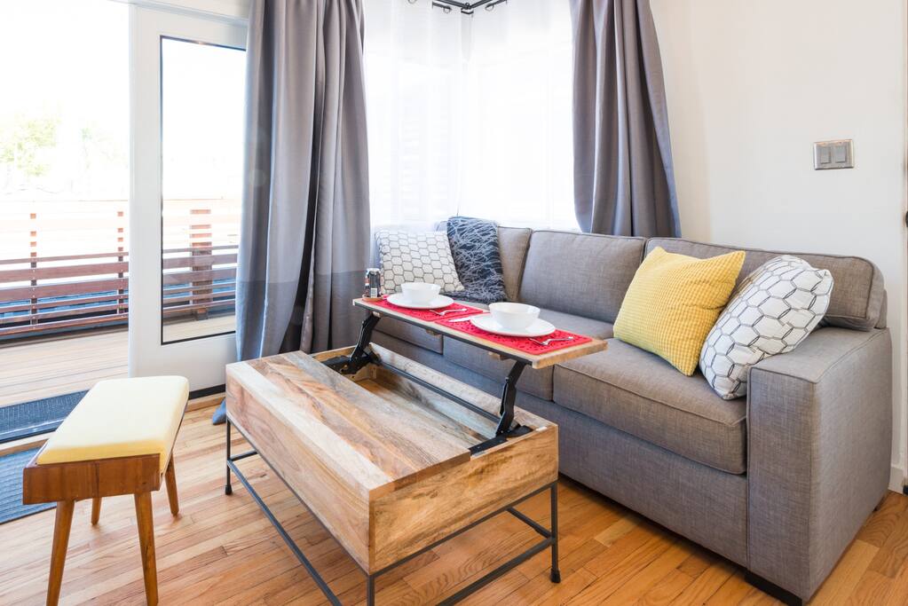 Daylit living room with french doors to deck. Coffee table doubles as dining