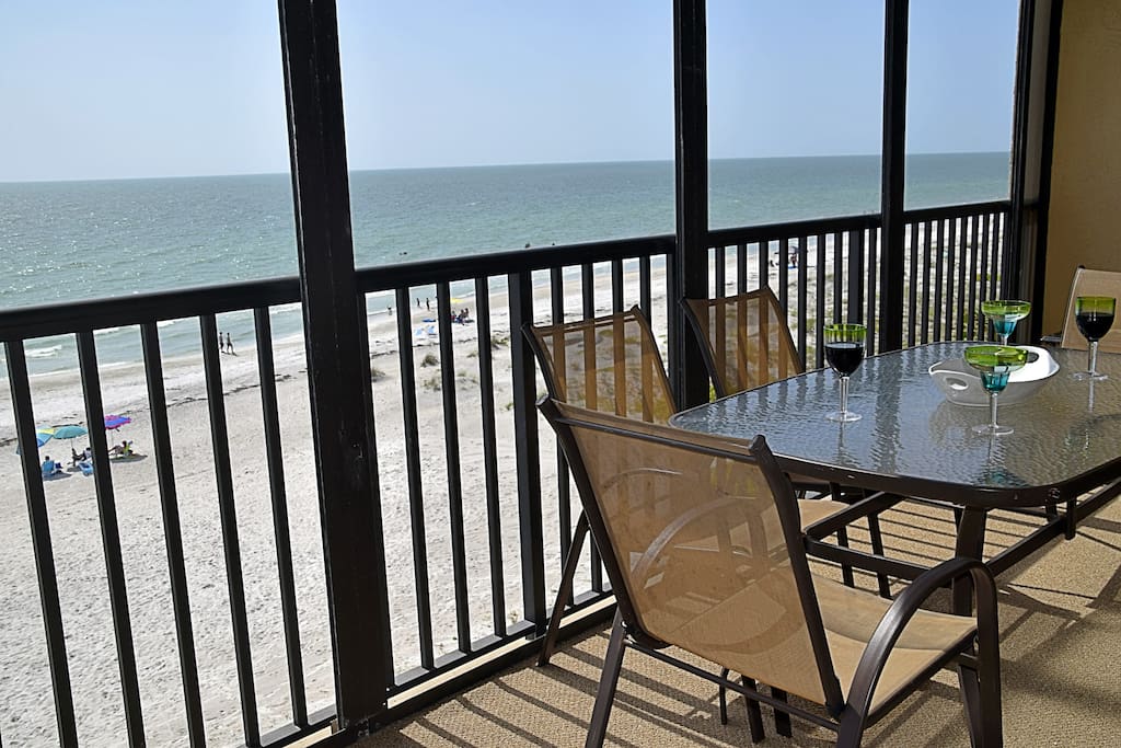 Beautiful beachfront views with a glider, large dining table, and chaise lounge