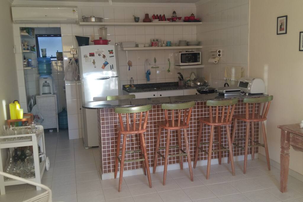 Cozinha com fogão, micro-ondas e apetrechos para cozinhar. logo atráz tanque de lavar roupa.