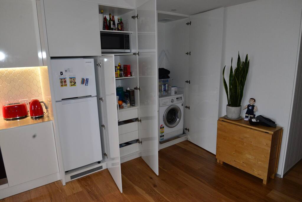 Cupboards in kitchen conceal fridge, microwave, washing machine, more.