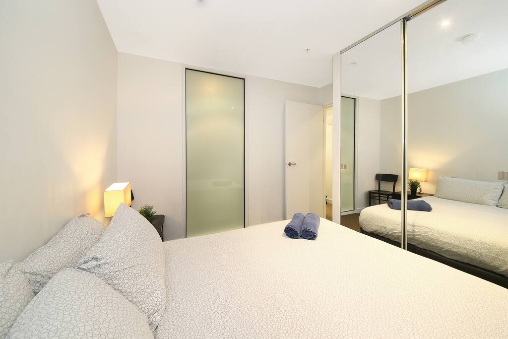 A bedroom with a queen sized bed & plush pillows.